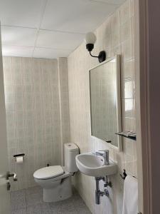 a bathroom with a toilet and a sink and a mirror at Hostal Porto Mar in Salou