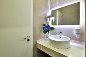 a white sink sitting under a mirror in a bathroom at Porto Domus Hotel in Porto