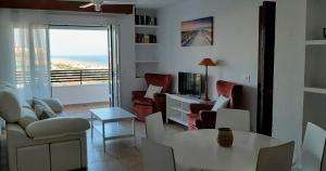 sala de estar con mesa, sillas y TV en Apartamento en la Playa de Punta Umbría, en Punta Umbría