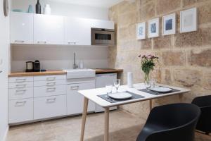 a kitchen with white cabinets and a table and chairs at Design & Cosy - Centre historique Ecusson in Montpellier