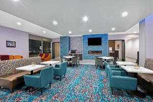 a hotel room with tables and chairs and a tv at La Quinta Inn & Suites DFW West-Glade-Parks in Euless