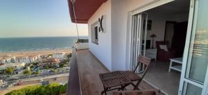 Un balcón con una silla y vistas al océano. en Apartamento en la Playa de Punta Umbría, en Punta Umbría