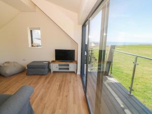 a living room with a tv and a large window at Glan Yr Afon in Holyhead