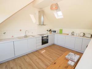 a kitchen with white cabinets and a wooden floor at Glan Yr Afon in Holyhead
