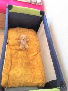 a teddy bear laying on a bed in a crib at Ferien Wohnung in der Eifel in Nideggen-Schmidt in Schmidt
