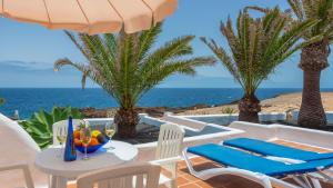a patio with a table and chairs and the ocean at Reyes Natur in Charco del Palo