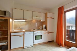 małą kuchnię z białymi urządzeniami i oknem w obiekcie Appartement Gratt w mieście Ellmau