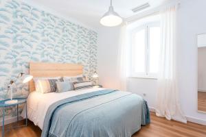 ein Schlafzimmer mit einem Bett mit einer blau-weißen Wand in der Unterkunft Genteel Home Plaza de la Marina in Málaga