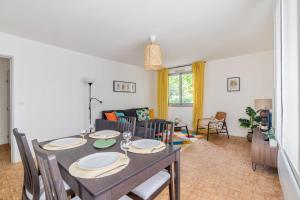 uma sala de jantar e sala de estar com mesa e cadeiras em Beautiful 1-bedroom w balcony and garden near Lyons city center Welkeys em Caluire-et-Cuire