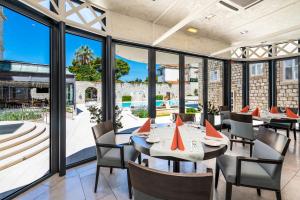 un restaurante con mesas, sillas y ventanas grandes en Hotel Lapad en Dubrovnik