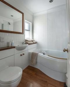 a white bathroom with a tub and a toilet and a sink at Cranborne House in Poole