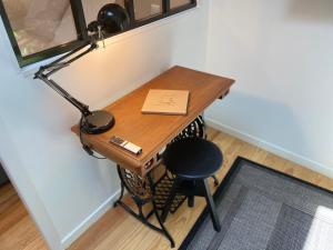 einen Schreibtisch mit einer Lampe, einem Buch und einem Stuhl in der Unterkunft Le Bistrot - Au Coeur d'Agen - Self Checkin - Wifi - Netflix - Smart TV - Luqs fr in Agen