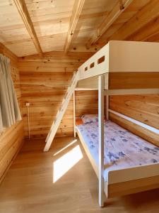 a bedroom with two bunk beds in a log cabin at Camping Piccolo Paradiso in Avegno