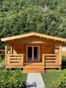 a wooden cabin with a large window in the grass at Camping Piccolo Paradiso in Avegno