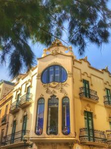 un edificio amarillo con ventanas y un árbol en Hotel Noucentista, en Sitges