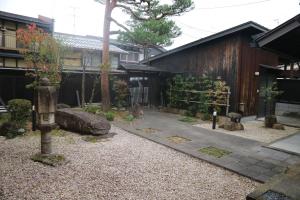 un jardín japonés con un camino de piedra y un edificio en Yoshiki Stay, en Furukawachō