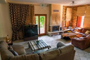 a living room with couches and a television and a fireplace at Chariklia's House with private pool in Káto Lekhónia