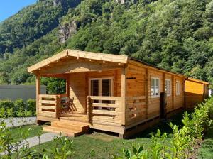 a wooden cabin in the grass with a mountain at Camping Piccolo Paradiso in Avegno
