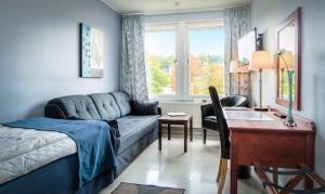 ein Wohnzimmer mit einem Sofa, einem Schreibtisch und einem Bett in der Unterkunft Hotel Sollefteå in Sollefteå
