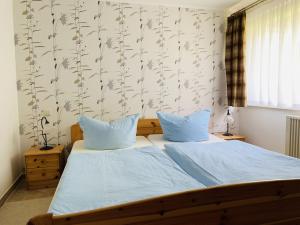 een slaapkamer met een bed met blauwe lakens en bloemenbehang bij Studio-Apartment Zacher 1 - 3 in Kühlungsborn