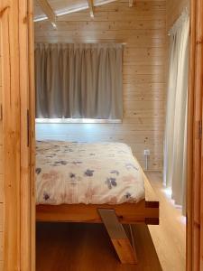 a bed in a wooden room with a window at Camping Piccolo Paradiso in Avegno