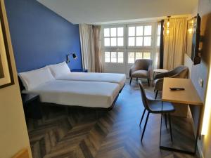 Habitación de hotel con cama, mesa y sillas en Hotel Alda Galería Coruña, en A Coruña