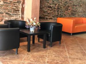 dos sillas negras y una mesa con un jarrón de flores en Apartamentos Albariño, en Vegadeo