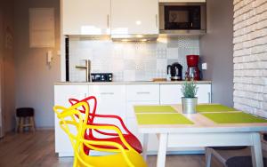 une cuisine avec une table et une chaise jaune et rouge dans l'établissement Apartamenty EverySky - Ogrodnicza 7-9, à Karpacz