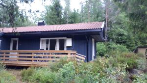a blue house with a wooden deck in a forest at HagestadHytteutleie Granheim in Birkeland