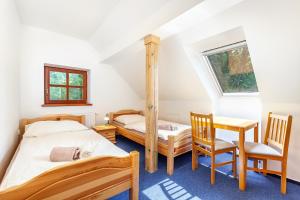 a bedroom with two beds and a table and chairs at Penzion Bačalský mlýn in Morašice