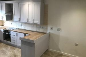 a kitchen with white cabinets and a wooden counter top at Bangor Home from Home 2bed house in Bangor +5 photos