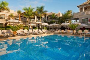 a swimming pool with chairs and umbrellas at a resort at Marylanza Suites & Spa in Playa de las Americas