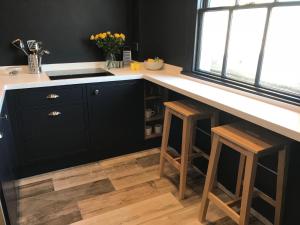 una cocina con armarios negros y una barra con taburetes en The Loft, Flat 3 en Bath