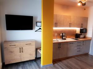 a kitchen with wooden cabinets and a tv on the wall at Baltic Seaside in Rewal +2 photos