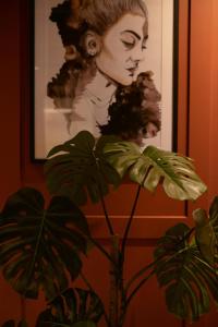 a plant in front of a painting of a woman at Home Again Apartments Kirkegata in Stavanger