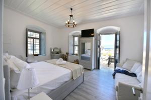 a white bedroom with a large bed and a balcony at Hydra Art Suites in Hydra