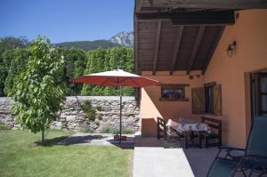 Un patio con una mesa y una sombrilla roja. en Residence Lago Blù -Riccio, en Pergine Valsugana