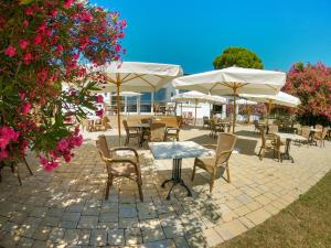 un patio con tavoli, sedie e ombrelloni bianchi di Sivinos Camping Boutique a Manerba del Garda