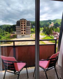 two chairs on a balcony with a view of a building at Snowman Studio Apartment Jahorina in Jahorina