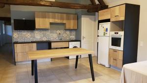 Il comprend une cuisine équipée d'une table en bois et d'un réfrigérateur blanc. dans l'établissement Domaine de la Loge, à Flacey-en-Bresse