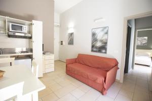 un salon avec un canapé rouge dans une cuisine dans l'établissement Le Plejadi, à Castellammare del Golfo