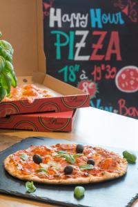 a pizza sitting on top of a table next to a box at ibis budget Nice Californie Lenval in Nice