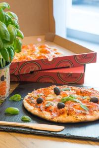 two pizzas sitting on a table with two boxes of pizza at ibis budget Nice Californie Lenval in Nice
