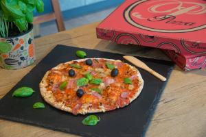 a pizza sitting on a table next to a box at ibis budget Nice Californie Lenval in Nice