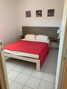 een slaapkamer met een bed met een rode deken bij Résidence mayflower in Le Grau-du-Roi