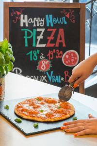 a person cutting a pizza with a pizza cutter at ibis budget Nice Californie Lenval in Nice