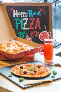 two pizzas sitting on a table with a box of pizza at ibis budget Nice Californie Lenval in Nice