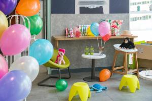 a room with balloons and a girl sitting in a chair at ibis budget Nice Californie Lenval in Nice