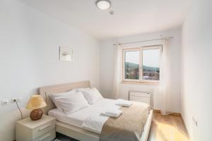 a white bedroom with a bed and a window at Crikvenica Residence Apartments and Rooms in Crikvenica