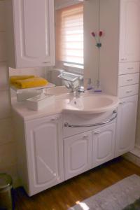 ein weißes Badezimmer mit einem Waschbecken und einem Spiegel in der Unterkunft Ferienhaus "Harzblick" in Halberstadt
